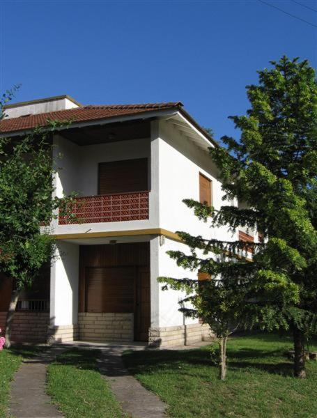 Una casa blanca con un árbol en frente.  en DLorena en Villa Gesell