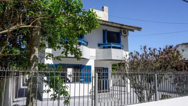 a white house with blue windows and a fence at Casa AZUL - A 70 Metros da Areia da Praia dos Ingleses - 6 Pessoas in Florianópolis