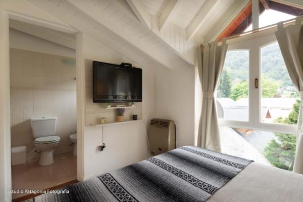 1 dormitorio con 1 cama y TV en la pared en M&T Centrico en San Martín de los Andes