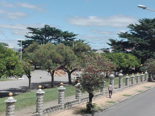 un hombre caminando por una acera junto a una valla en Departamento Serrano en Tandil