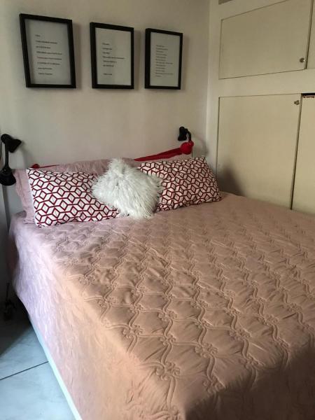 1 cama con edredón rosa y almohadas en Amelie Poulin Apartamento Beach, en Río de Janeiro