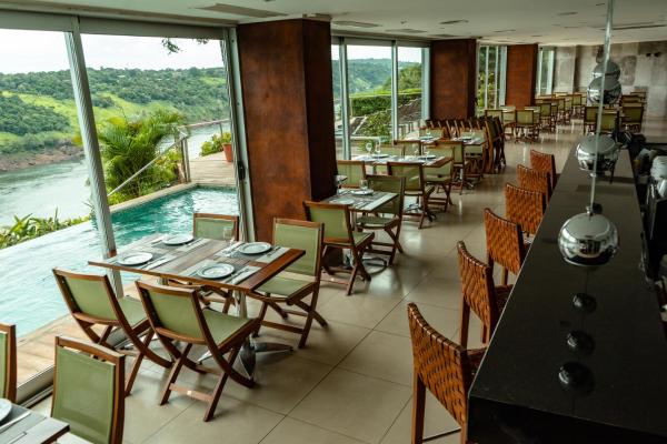 un restaurante con mesas y sillas y vistas al agua en Hotel Guaminí Misión en Puerto Iguazú