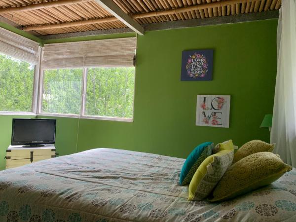 Dormitorio verde con cama y TV en Pensamientos del alma en Balneario Mar Azul