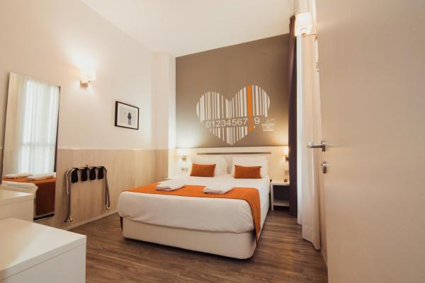 Habitación de hotel con cama con manta naranja en Hostal Live Barcelona, ​​en Barcelona