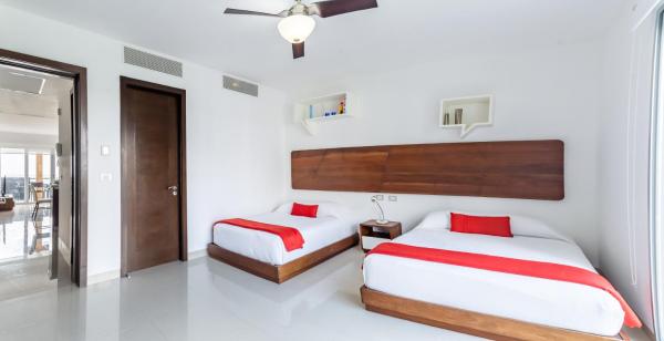 2 camas en una habitación con paredes blancas y almohadas rojas en Z Casa AltaMar Norte condo, en Playa del Carmen