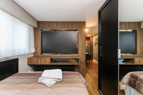 a bedroom with a bed and a flat screen tv at Studio Berlin - Central - 7th012 in Curitiba