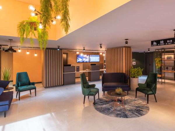 a living room filled with furniture and a large window at ibis Curitiba Batel in Curitiba