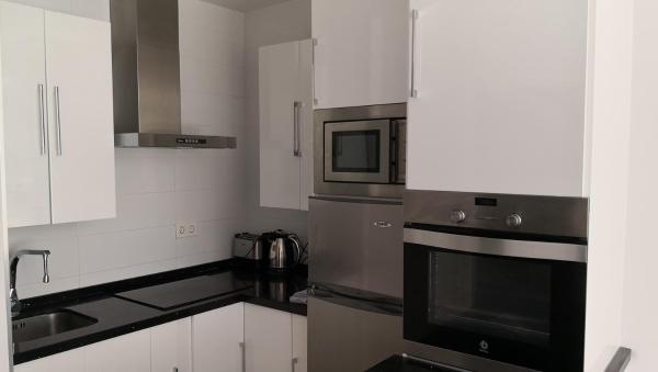 una cocina con armarios blancos y un aparato de acero inoxidable en Skol 320C by Completely Marbella, en Marbella