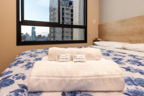 a bedroom with two towels on a bed with a window at Studio Serra do Mar - Central - AYN029 in Curitiba