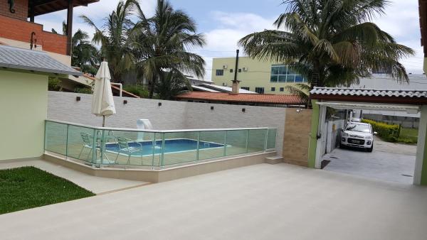 a balcony with a swimming pool and a umbrella at Casa com Piscina em Ingleses, para 09 pessoas in Florianópolis