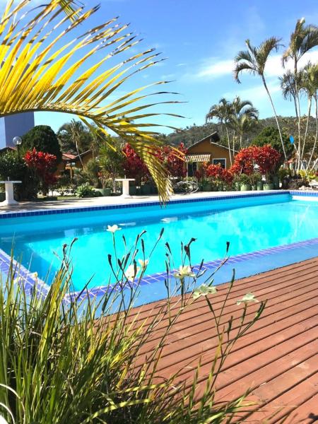 a blue swimming pool with a wooden deck and plants at Casa Chale 10 Florianópolis in Florianópolis