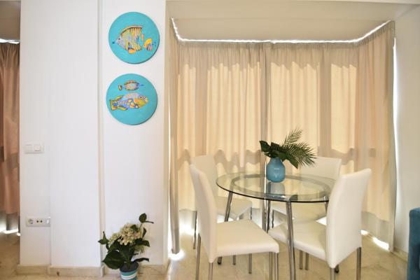 comedor con mesa de cristal y sillas blancas en Bonito apartamento a 5min.  del centro histórico, en Málaga