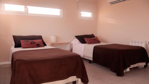 un dormitorio con dos camas con sábanas marrones y ventanas en el Punto Playa de Villa Gesell