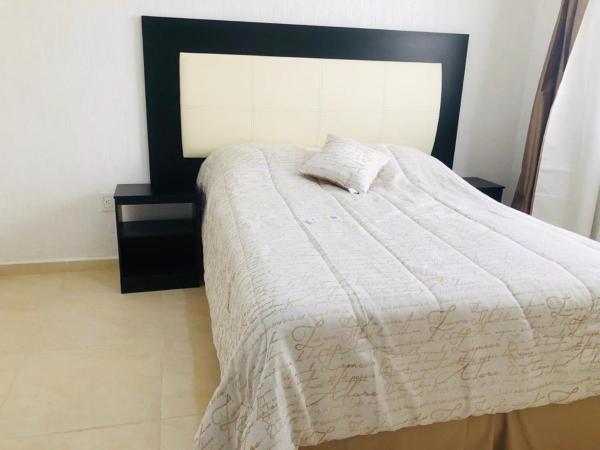 1 dormitorio con cama blanca y cabezal negro en La Llar que deseas para vacaciones., en Cancún