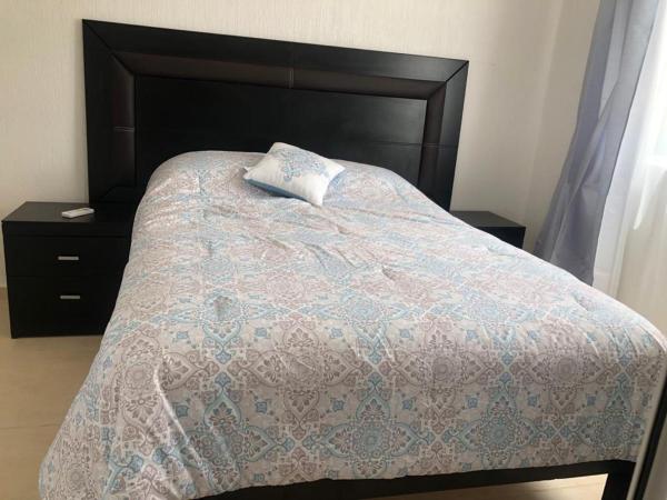 1 cama con edredón azul y cabezal negro en La Llar que deseas para vacacionar., en Cancún