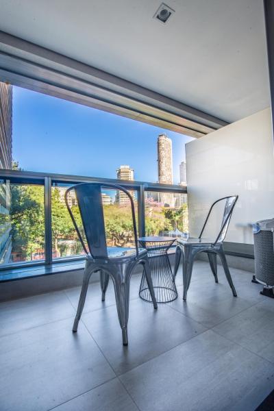 2 sillas y una mesa en una habitación con ventanas en 360 Suítes República - Apartamentos mobiliados, en São Paulo