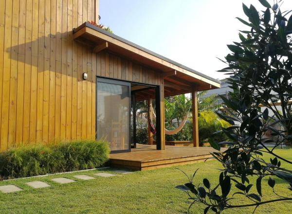 a small house with a large glass door in a yard at Exclusive EcoHouse! Privacy 100 m Praia Campeche in Florianópolis