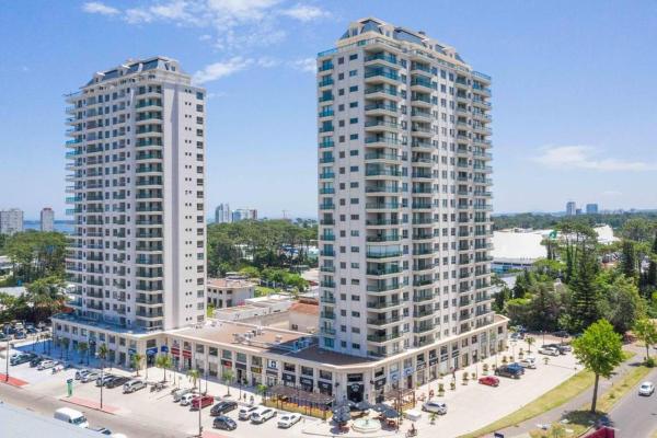 dos edificios blancos altos al lado de un estacionamiento en Monoambiente de lujo en Place Lafayette - Ganadores del premio Award 2021, en Punta del Este