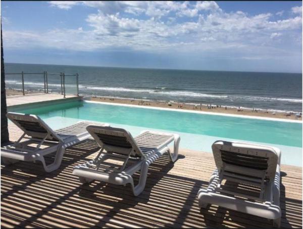 2 sillas y una piscina junto al océano en Los Pinos Pinamar en Pinamar