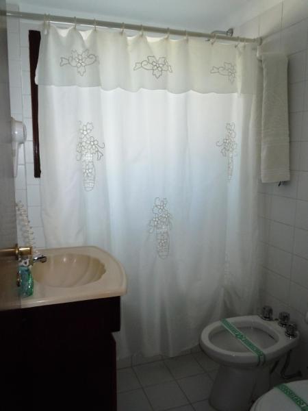 y baño con cortina de ducha blanca y aseo. en Las Araucarias en Pinamar