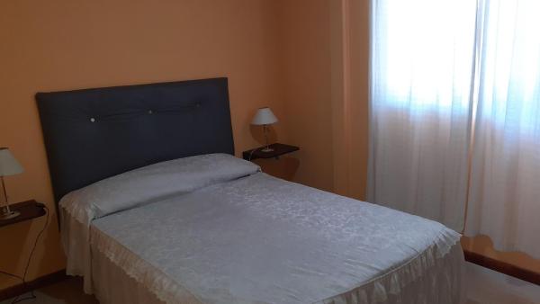 1 dormitorio con 1 cama con cabezal azul y ventana a Bien al Sur en Villa Gesell