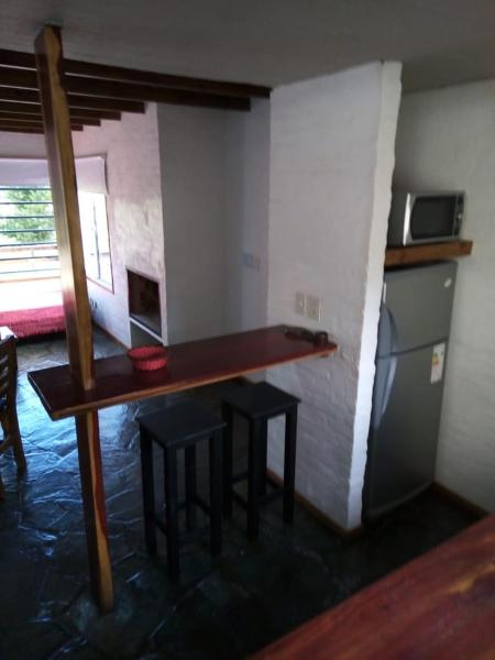 una cocina con mesa y taburetes en una habitación de DÚPLEX EN EL SUR en Villa Gesell