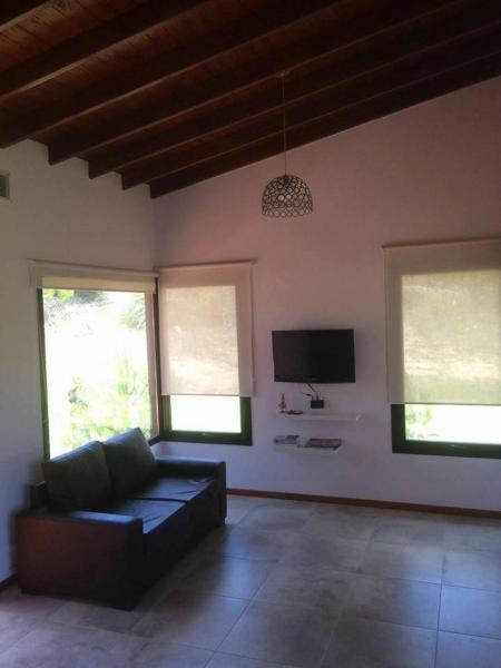 sala de estar con sofá y TV de pantalla plana en Pampa Sur Casas de Playa en Las Gaviotas