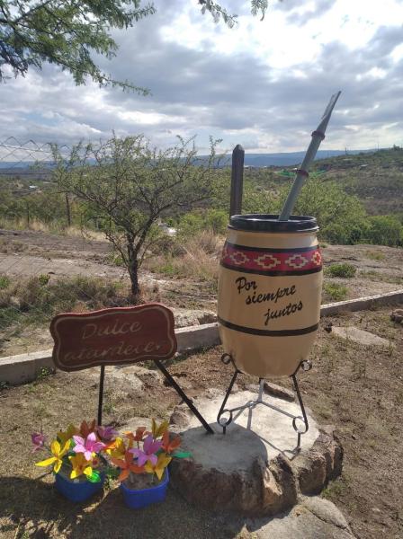 un mortero y una plaga con un cartel y flores en Cabañas Dulce Atardecer, en Villa Carlos Paz