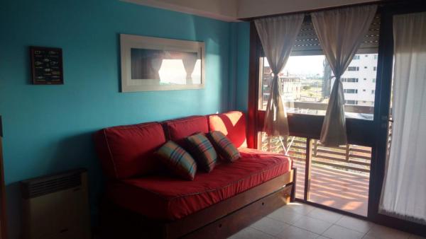 Sofá rojo sentado en una habitación con ventana en Departamento con Vista al Mar en Mar del Plata