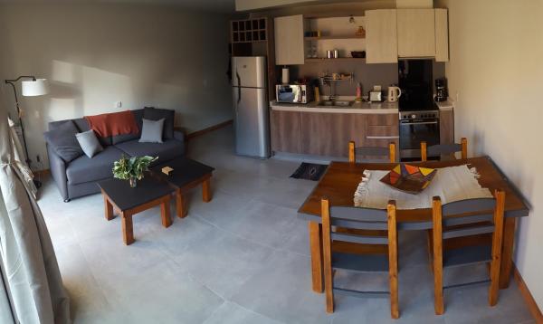 cocina y sala de estar con mesa y sofá. en UMAIN KAYU en San Martín de los Andes