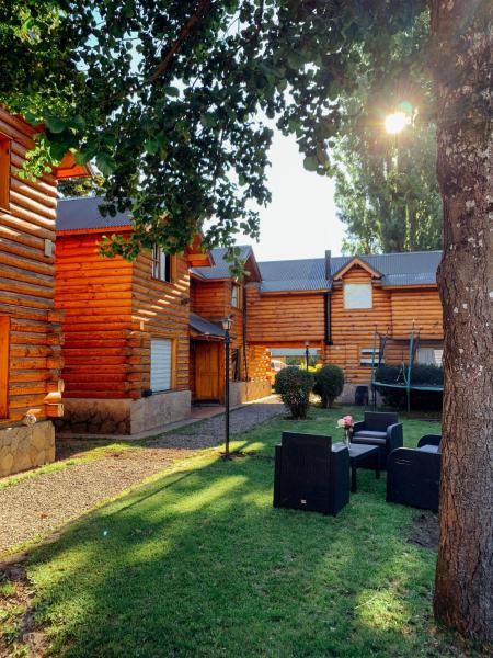 una casa con un patio con sillas y un árbol en Cabañas de Troncos en San Martín de los Andes