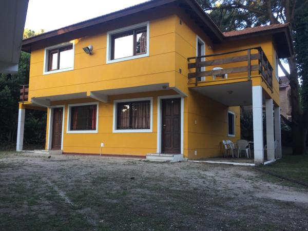una casa amarilla con un balcón en frente a Acuarela en Villa Gesell