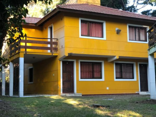 una casa amarilla con tejado rojo en Acuarela en Villa Gesell