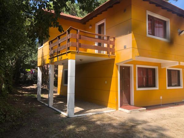 una casa amarilla con un balcón encima de Acuarela en Villa Gesell
