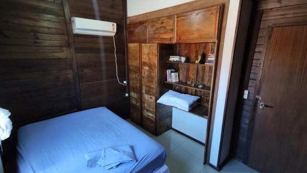 a small room with a bed and a book shelf at Casa no Campeche com Piscina in Florianópolis