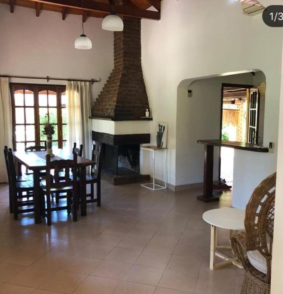 sala de estar con mesa y chimenea en Los zorzales quinta Chascomus en Chascomús