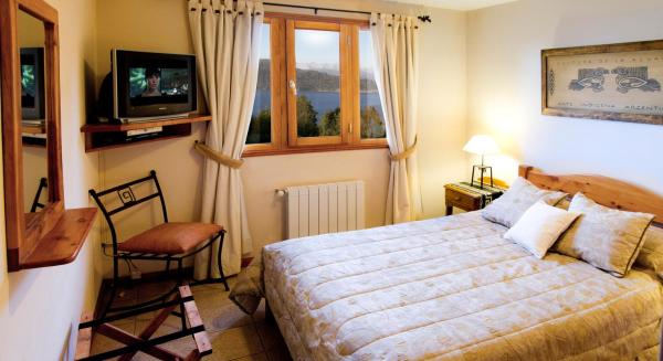 1 dormitorio con 1 cama, TV y silla en Bungalows Buena Vista en San Carlos de Bariloche