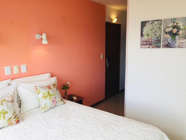a bedroom with orange walls and a bed with pillows at San Remo Terrazas Hotel in Piriápolis