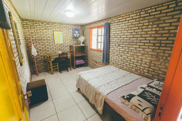 a bedroom with a bed and a dresser at Chalés Caminhos Do Rosa in Praia do Rosa