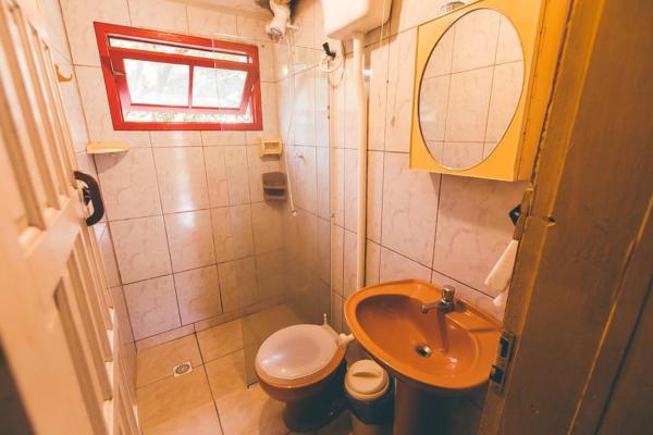 a bathroom with a toilet and a sink at Chalés Caminhos Do Rosa in Praia do Rosa