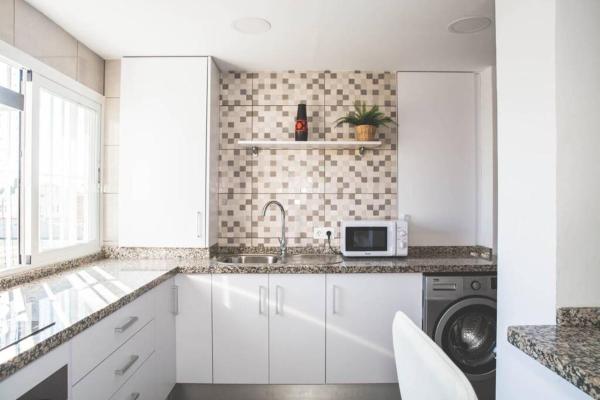 cocina blanca con fregadero y lavavajillas en Luminoso Apartamento 3hab en Pedregalejo Playa, en Málaga