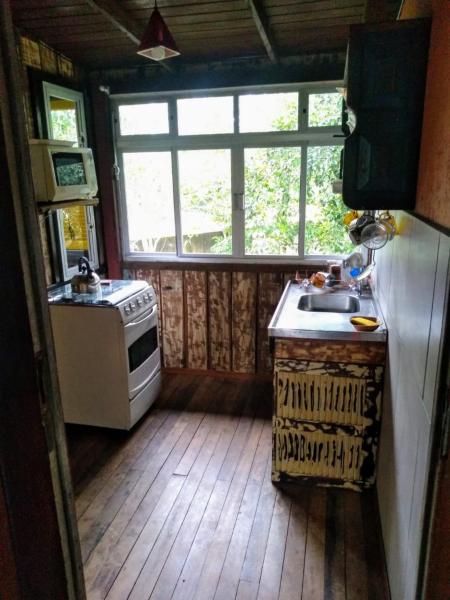 a kitchen with a sink, stove and a window at Chalés Caminhos Do Rosa in Praia do Rosa