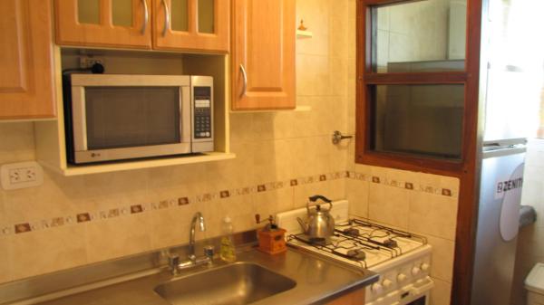cocina con fregadero y microondas en el Departamento Villa Gesell Norte sobre Playa y 310 Vista al Mar en Villa Gesell
