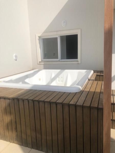 bañera en una terraza de madera con ventana en duplex mariscal, en Bombinhas