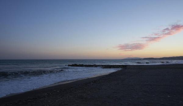 una playa al atardecer con el océano y las olas en Casa María, en Málaga