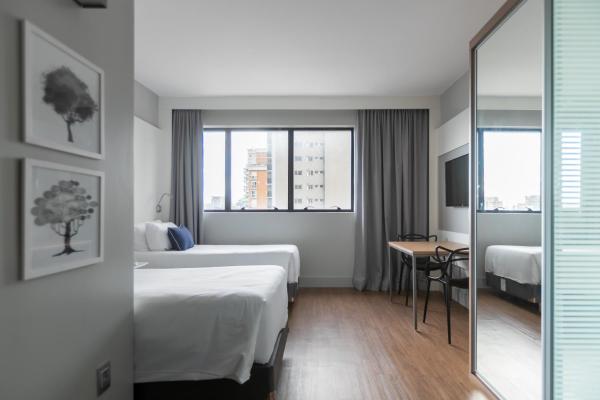 a hotel room with two beds and a mirror at Studio Premium Batel Twin - HSB001 in Curitiba