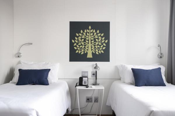 two beds in a room with a tree picture on the wall at Studio Premium Batel Twin - HSB001 in Curitiba