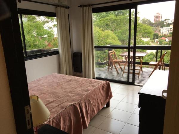 1 dormitorio con 1 cama y balcón con mesa en Los Paraisos en Villa Gesell
