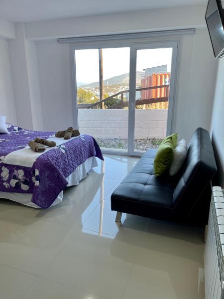 un dormitorio con una cama y un sofá y una ventana en Alvere lll Temporary Apartments Ushuaia en Ushuaia