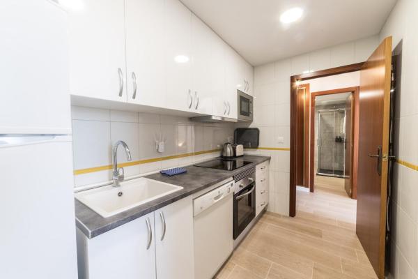 una cocina con armarios blancos y fregadero en Moonkey - Apartamento Las Mandarines, en Benidorm